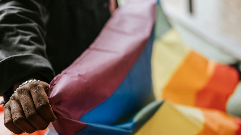 Crop faceless African American homosexual male in casual clothes showing colorful rainbow flag on street, tags: prüfen - pexel